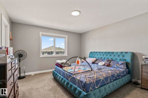 Carpeted room with a double-pane window, light gray wall paint, white trim, and a flush-mount ceiling light fixture - 5142 23A Avenue, Edmonton, AB - Indoor Photo Showing Bedroom