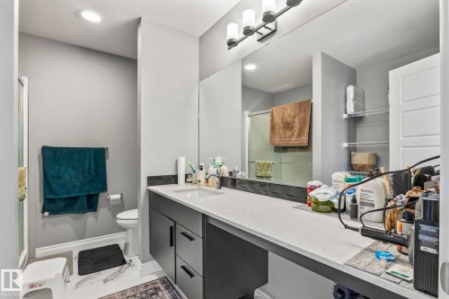 Bathroom featuring a spacious vanity with an undermount sink, light-toned countertop, and dark cabinetry - 5142 23A Avenue, Edmonton, AB - Indoor Photo Showing Bathroom