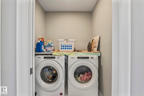 Dedicated laundry area featuring a front-loading washer and dryer set - 5142 23A Avenue, Edmonton, AB - Indoor Photo Showing Laundry Room