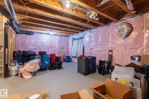 Unfinished basement space featuring exposed wooden joists, pink insulation, and a concrete floor - 5142 23A Avenue, Edmonton, AB - Indoor Photo Showing Basement