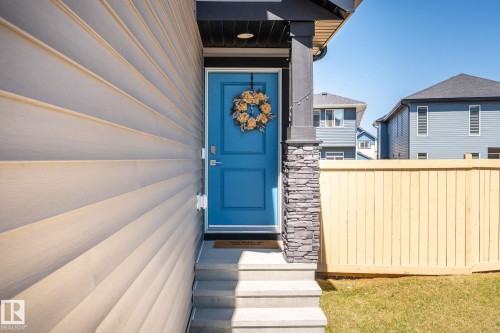 Entryway featuring a blue paneled door, stone-clad pillar, and light horizontal siding - 5142 23A Avenue, Edmonton, AB - Outdoor
