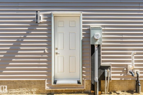 Exterior wall featuring horizontal siding, a paneled entry door, and an exterior wall sconce - 5142 23A Avenue, Edmonton, AB - Outdoor