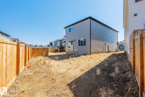 Spacious rear yard with natural wood privacy fencing, a two-story home with light gray siding, and a rear deck - 5142 23A Avenue, Edmonton, AB - Outdoor With Exterior