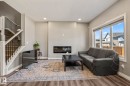 Living room featuring wood-finish flooring, a contemporary fireplace, and a large window - 5142 23A Avenue, Edmonton, AB  - Indoor With Fireplace 