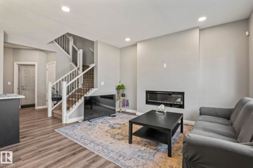 Spacious living area featuring wood-finish flooring, recessed lighting, and a contemporary linear fireplace - 5142 23A Avenue, Edmonton, AB - Indoor With Fireplace