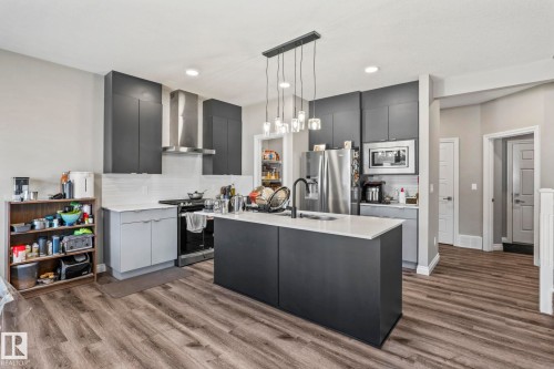 Contemporary kitchen featuring a dark gray island with a white countertop and a matte black faucet - 5142 23A Avenue, Edmonton, AB - Indoor Photo Showing Kitchen With Upgraded Kitchen