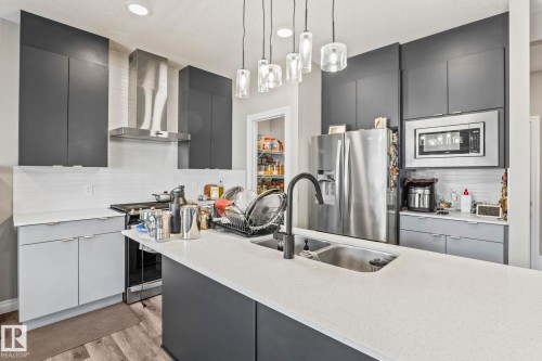 Modern kitchen featuring dark gray upper cabinetry, light gray lower cabinetry, and a light-toned countertop - 5142 23A Avenue, Edmonton, AB - Indoor Photo Showing Kitchen With Double Sink With Upgraded Kitchen