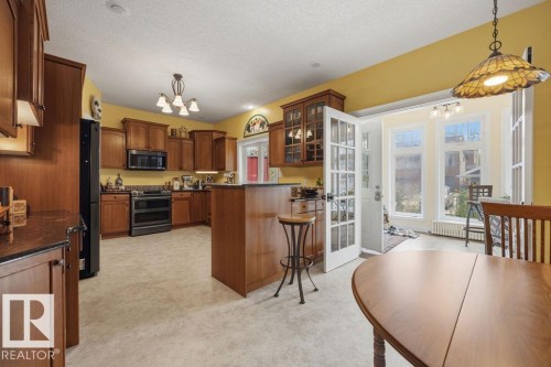 The gorgeous kitchen features high quality cabinetry with custom pullout shelving in the lowers, granite countertops, raised dishwasher, corner pantry, newer high end appliances, built-in desk, and looks out at the south facing back yard. - 11137 81 Avenue, Edmonton, AB - Indoor