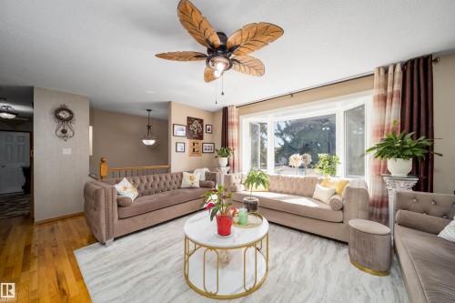 Spacious living area featuring a large bay window, hardwood flooring, and a decorative ceiling fan - 14808 96 Street, Edmonton, AB - Indoor Photo Showing Living Room