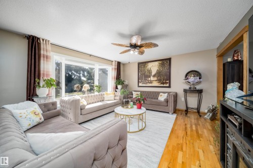 Spacious living area featuring a large bay window, wood-finish flooring, a ceiling fan with integrated lighting, and neutral wall tones - 14808 96 Street, Edmonton, AB - Indoor Photo Showing Living Room