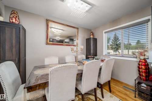 Dining area featuring a rectangular wood-finish table, upholstered chairs with studded trim, and a framed wall mirror - 14808 96 Street, Edmonton, AB - Indoor Photo Showing Dining Room