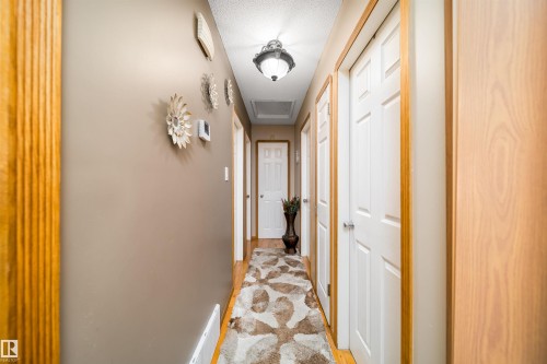 Hallway featuring wood-finish flooring, light-colored walls, white paneled doors with wood trim, and an overhead flush-mount light fixture - 14808 96 Street, Edmonton, AB - Indoor Photo Showing Other Room