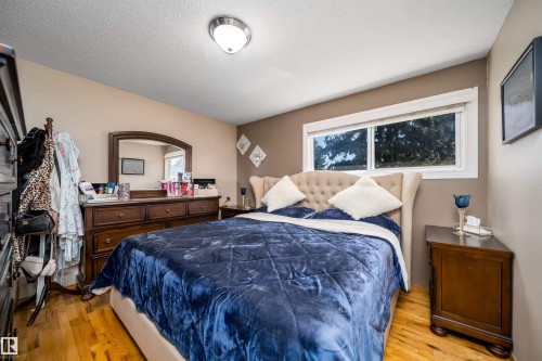 Spacious bedroom with wood-finish flooring, neutral paint palette, and a large window - 14808 96 Street, Edmonton, AB - Indoor Photo Showing Bedroom