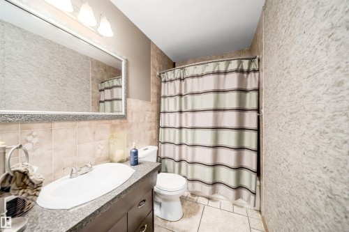 Full bathroom featuring a vanity with an integrated sink and dark cabinetry - 14808 96 Street, Edmonton, AB - Indoor Photo Showing Bathroom