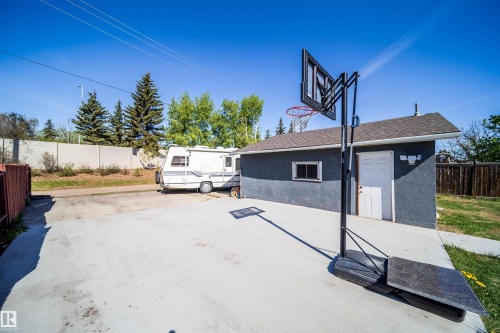 Detached garage with stucco exterior and shingled roof, featuring a white access door and a horizontal window - 14808 96 Street, Edmonton, AB - Outdoor