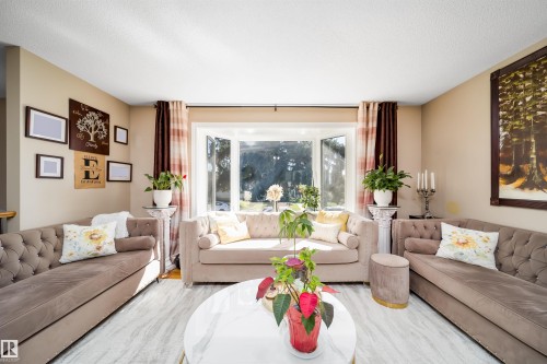Spacious living area featuring a large bay window, light-toned walls, and grey wood-finish flooring - 14808 96 Street, Edmonton, AB - Indoor Photo Showing Living Room