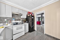 Kitchen featuring white cabinetry, a tile backsplash, a range with an overhead hood, and gray tiled flooring - 