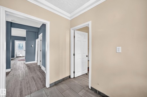 Hallway featuring neutral and accent wall paint, crown molding, and wood-finish flooring - 12627 71 Street Nw, Edmonton, AB 