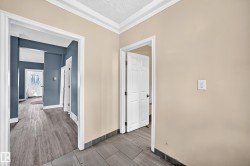 Hallway featuring neutral and accent wall paint, crown molding, and wood-finish flooring - 