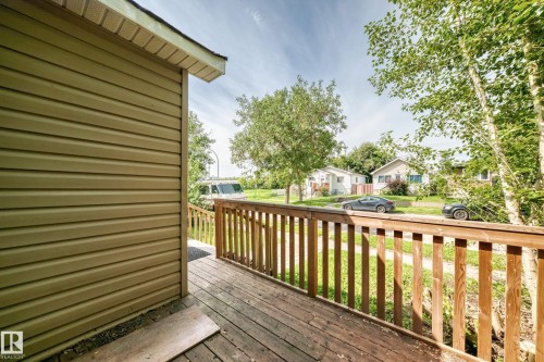 Exterior featuring horizontal siding, wooden deck, wooden railing, and mature trees - 12627 71 Street Nw, Edmonton, AB 