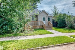 Siding exterior featuring a pitched roof, front porch with wood railings, and concrete walkway - 