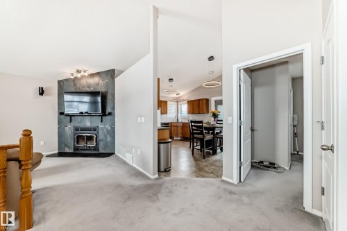 Living area featuring a fireplace with a stone surround, vaulted ceilings, and light-colored carpeting - 8008 97 St, Morinville, AB - Indoor With Fireplace