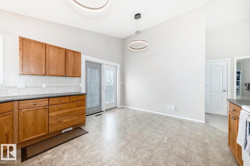 The kitchen features wood cabinetry, a tiled backsplash, and a tiled floor - 8008 97 St, Morinville, AB - Indoor Photo Showing Kitchen