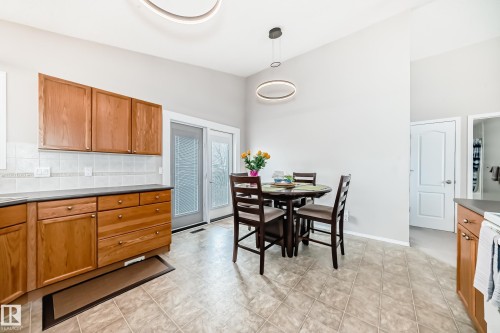 This kitchen features wood cabinetry, a tiled backsplash, and light-colored floor tiles - 8008 97 St, Morinville, AB - Indoor