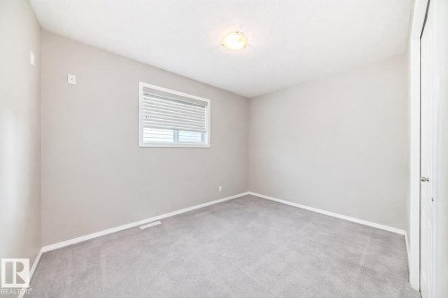 This room features light grey walls, grey carpet flooring, and a window with blinds providing natural light - 8008 97 St, Morinville, AB - Indoor Photo Showing Other Room