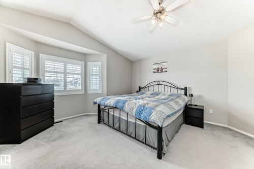 This room features light-colored walls and carpeting, a sloped ceiling, and a ceiling fan - 8008 97 St, Morinville, AB - Indoor Photo Showing Bedroom