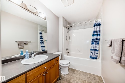 This bathroom features a vanity with a large mirror, an integrated sink, and wood cabinetry - 8008 97 St, Morinville, AB - Indoor Photo Showing Bathroom