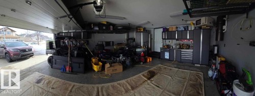 The garage features an overhead garage door, concrete flooring, and extensive built-in cabinetry for storage - 8008 97 St, Morinville, AB - Indoor Photo Showing Garage