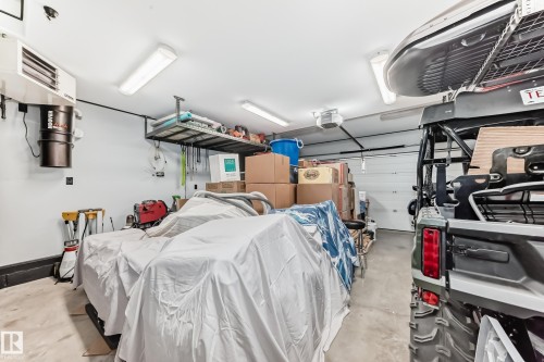 The garage features a white sectional overhead door, overhead fluorescent lighting, and a wall-mounted heater - 8008 97 St, Morinville, AB - Indoor Photo Showing Garage