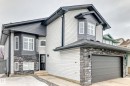 The property features a two-story exterior with light-colored siding, dark gray accents, and stone detailing around the garage and bay windows - 8008 97 St, Morinville, AB  - Outdoor 
