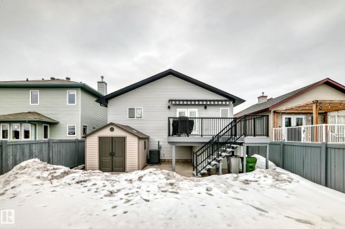 The property features a rear deck with black railings and stairs, a retractable awning, and a storage shed in the yard - 8008 97 St, Morinville, AB - Outdoor