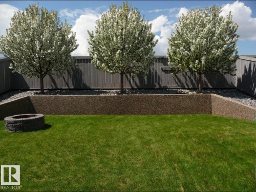 The property features a well-maintained lawn, a stone fire pit, and a retaining wall - 8008 97 St, Morinville, AB - Outdoor