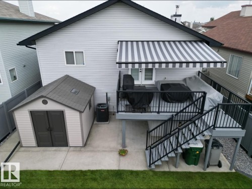 The property features a concrete patio area, a shed with double doors, and a deck with black railings - 8008 97 St, Morinville, AB - Outdoor With Exterior