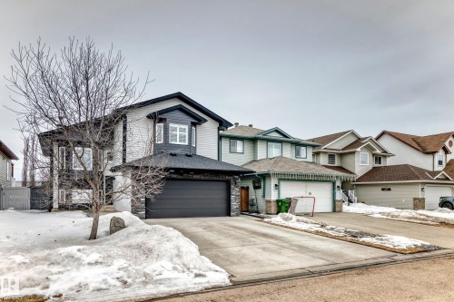 The property features a two-story design with a dark gray garage door, light-colored siding, and dark trim details - 8008 97 St, Morinville, AB - Outdoor With Facade