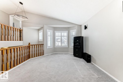 Spacious room featuring light grey carpeting, light grey walls, and a bay window with white plantation shutters - 8008 97 St, Morinville, AB - Indoor Photo Showing Other Room