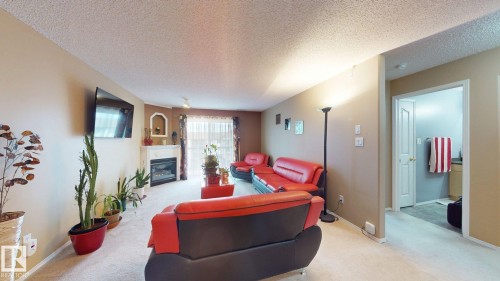 Living area featuring a fireplace with a mantel, a recessed wall niche, and patio door access - 405 16303 95 Street Nw, Edmonton, AB - Indoor Photo Showing Other Room With Fireplace