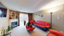 Living room featuring a fireplace with a white mantel, sliding glass door, light-colored carpet, and an accent wall - 