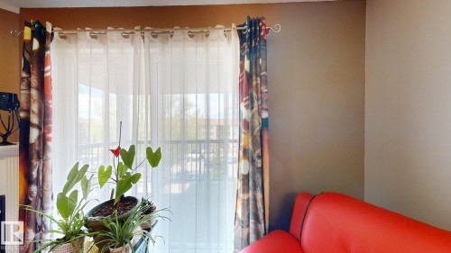 Floor-to-ceiling balcony doors with sheer and patterned curtain panels - 405 16303 95 Street Nw, Edmonton, AB - Indoor