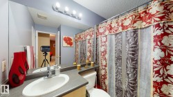 Bathroom featuring a single basin vanity with a laminate countertop, an integrated mirror spanning the wall, and a four-bulb vanity light fixture - 