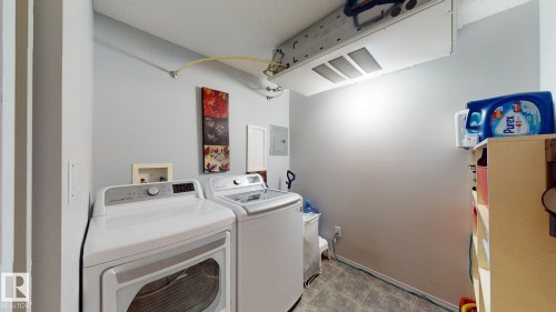 Dedicated laundry area featuring a washer and dryer, light gray walls, and tile flooring - 405 16303 95 Street Nw, Edmonton, AB - Indoor Photo Showing Laundry Room