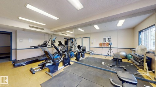 Dedicated fitness room featuring a mirrored wall, recessed lighting, and a rubber mat flooring section - 405 16303 95 Street Nw, Edmonton, AB - Indoor Photo Showing Gym Room