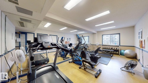 Fitness room featuring recessed lighting, a mirrored wall, and wood-finish flooring - 405 16303 95 Street Nw, Edmonton, AB - Indoor Photo Showing Gym Room