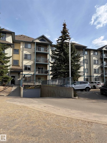 Multi-story condominium building featuring a light-colored facade with dark trim - 405 16303 95 Street Nw, Edmonton, AB - Outdoor With Balcony With Facade