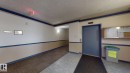 Elevator access in a common area featuring wall-mounted lighting, a display case, and mixed flooring with tile and patterned carpet - 405 16303 95 Street Nw, Edmonton, AB  - Indoor Photo Showing Other Room 