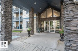 Building entrance featuring stacked stone columns and facade, double glass entry doors, and a covered portico - 
