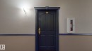 Painted door with gold-toned hardware, overhead wall sconce, and textured wall finish - 405 16303 95 Street Nw, Edmonton, AB  -  Photo Showing Other Room 
